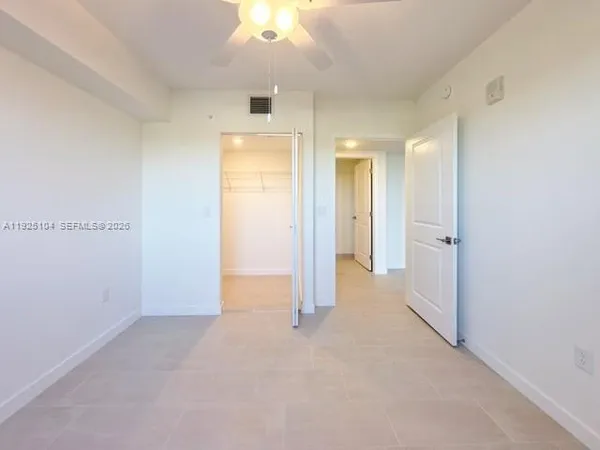 an empty room with chandelier fan and windows