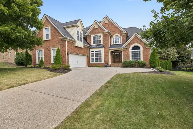 a front view of a house with a garden and trees