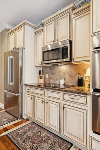 a kitchen with stainless steel appliances granite countertop a stove oven and white cabinets with wooden floor