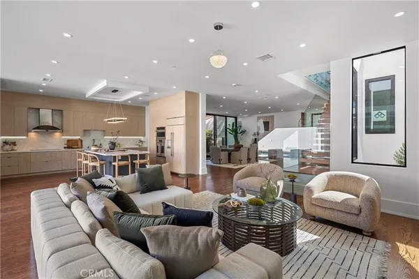 a kitchen with stainless steel appliances kitchen island granite countertop a refrigerator a stove a microwave oven with a dining table and chairs with wooden floor