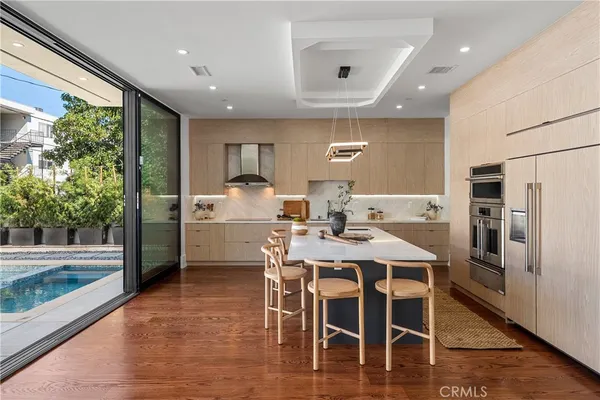 a kitchen with stainless steel appliances kitchen island granite countertop a table chairs sink and cabinets
