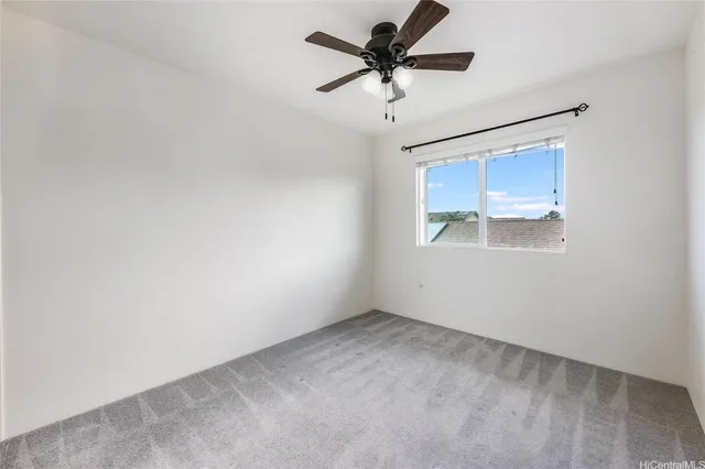 an empty room with a fan & a window