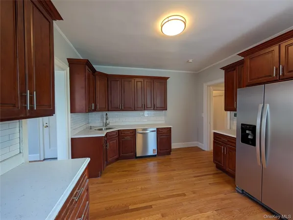 a kitchen with stainless steel appliances granite countertop a refrigerator a sink dishwasher a stove with wooden cabinets and floor