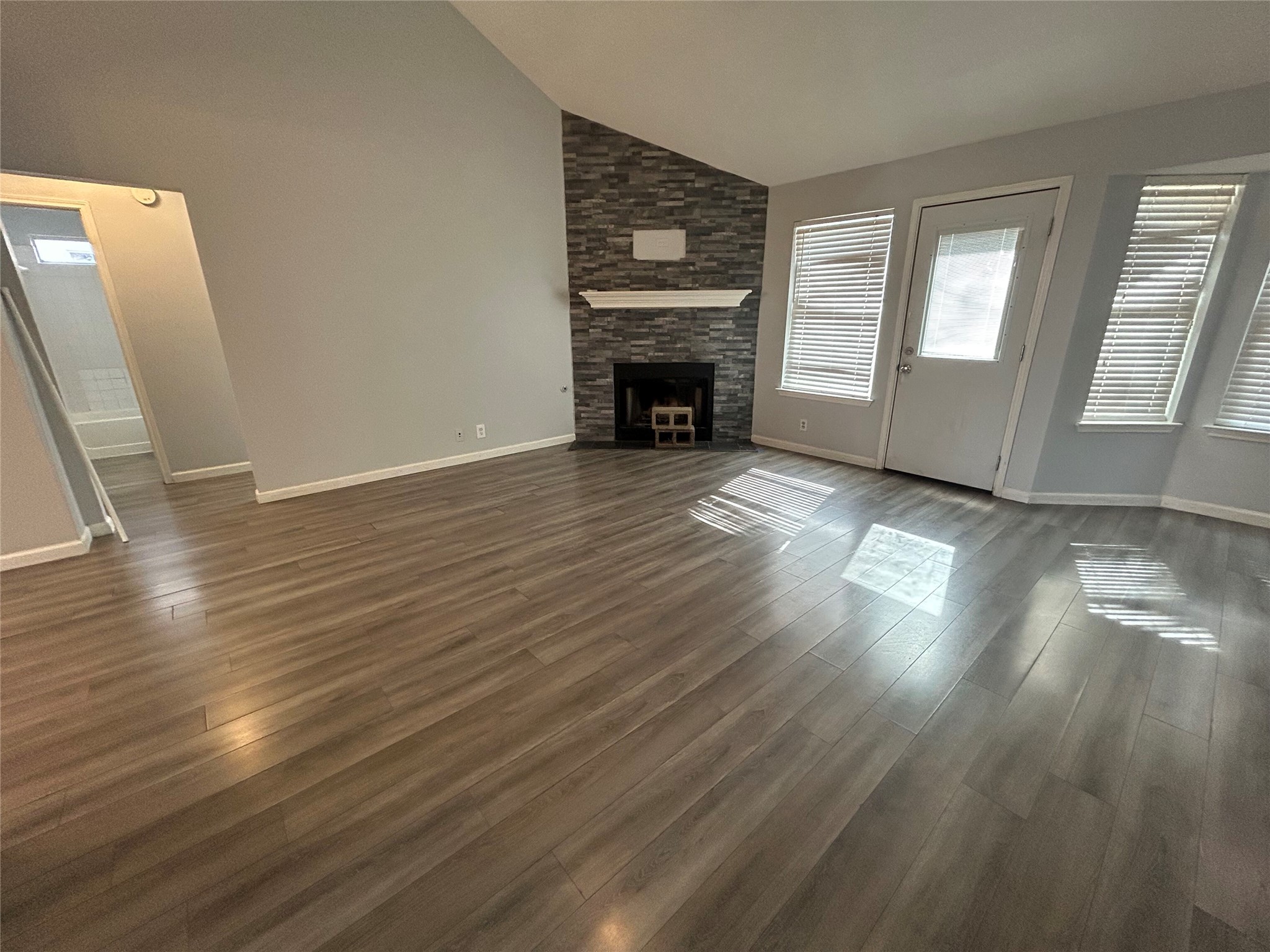 516 Jefferson Lane Georgetown, TX 78626 - Photo 2 of 16 Unfurnished living room featuring dark wood-style flooring, lofted ceiling, and a fireplace
