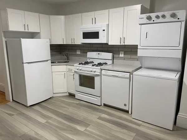 a kitchen with cabinets appliances and wooden floor