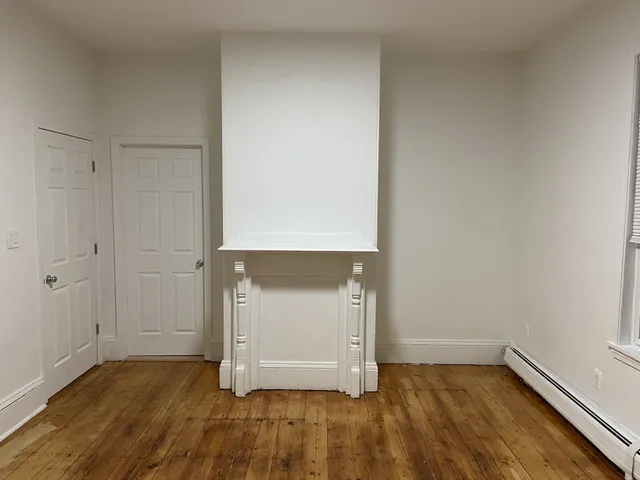 an empty room with wooden floor and cabinet