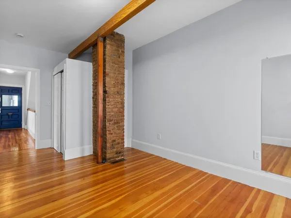 a view of an empty room with wooden floor and entryway