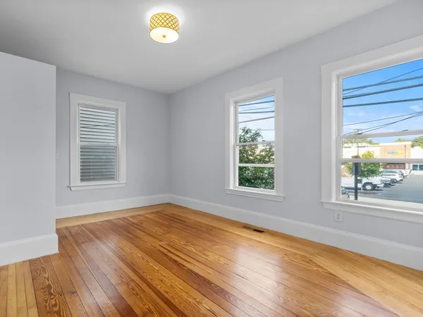 a view of empty room with window and wooden floor