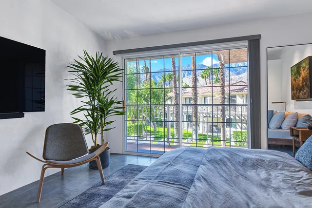 a bedroom with a bed a television and potted plants