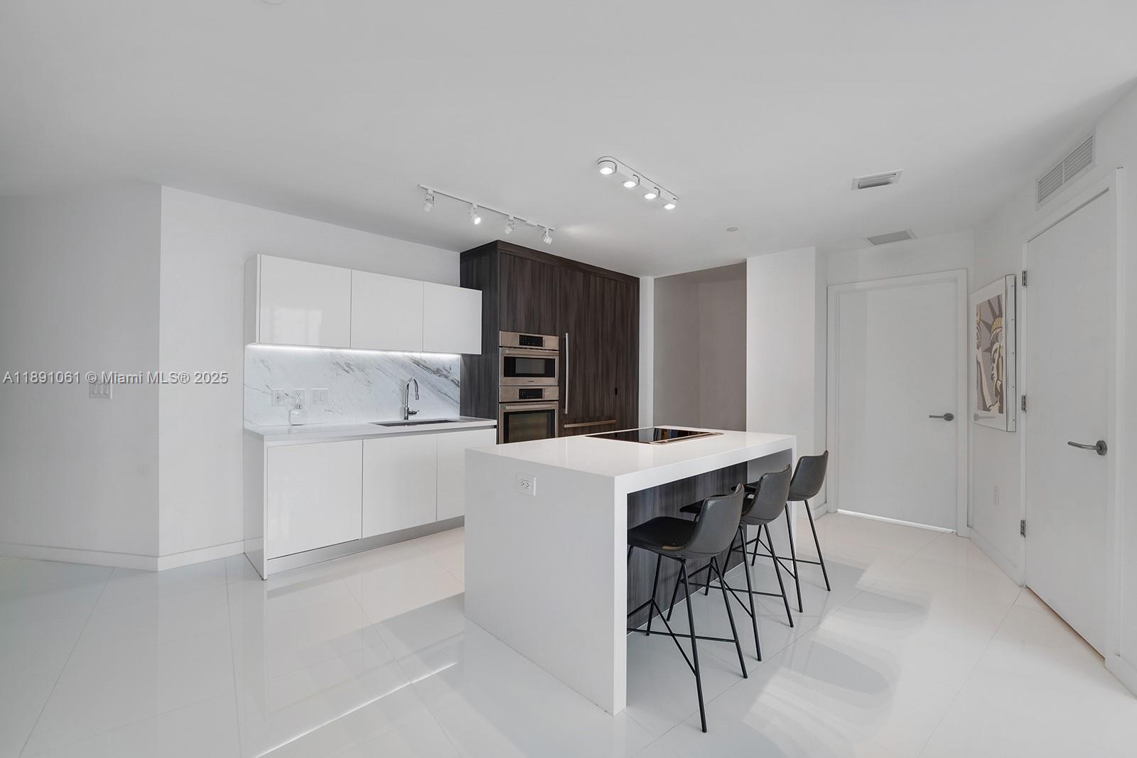 851 Northeast 1st Avenue, Unit 4403 Miami, FL 33132 - Photo 6 of 31 a kitchen with a stove a refrigerator and a table