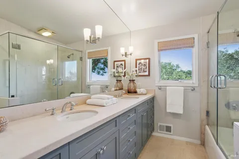 a bathroom with a sink double vanity granite tub shower and a mirror