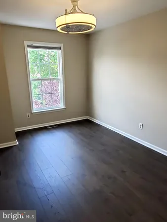 an empty room with wooden floor chandelier fan and windows