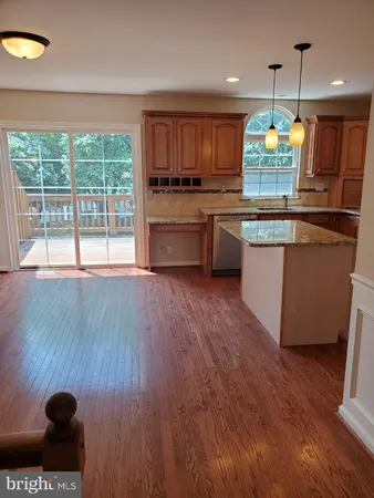 a kitchen with kitchen island granite countertop wooden floors stainless steel appliances and sink