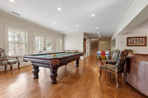 a room with furniture pool table wooden floor and windows