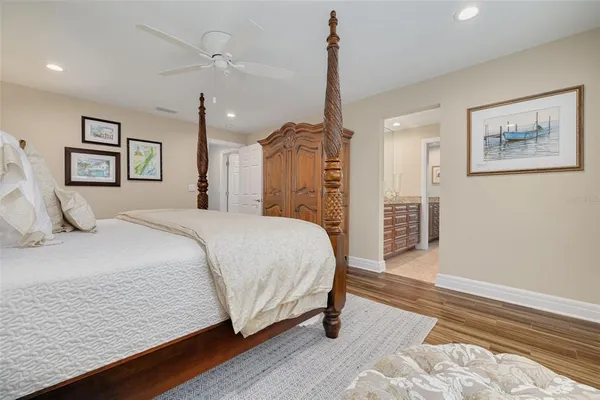 a spacious bedroom with a bed painting on wall and a potted plant