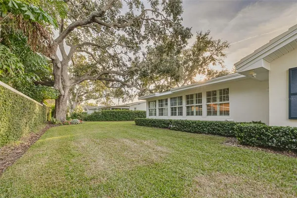 a view of a house next to a big yard and large trees
