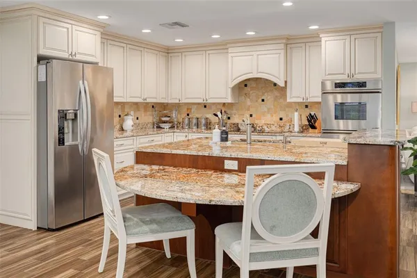 a kitchen with stainless steel appliances granite countertop a table chairs sink refrigerator and microwave