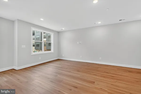 a view of an empty room with wooden floor and windows