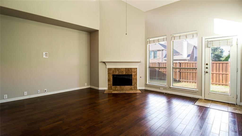 8698 Fisher Road Frisco, TX 75033 - Photo 13 of 33 an empty room with wooden floor fireplace and windows
