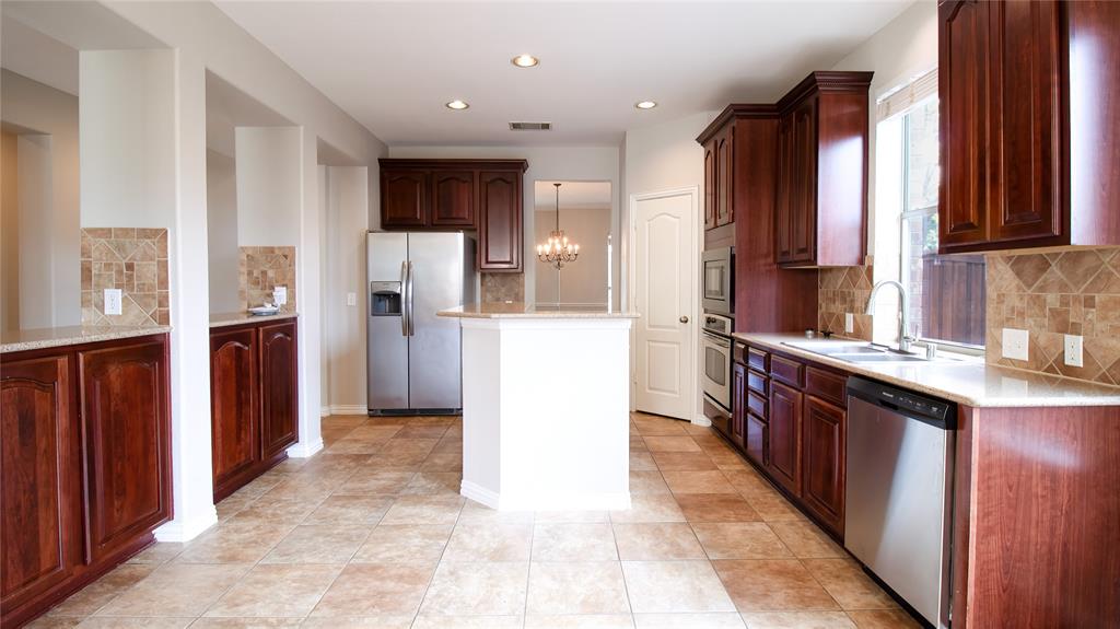 8698 Fisher Road Frisco, TX 75033 - Photo 10 of 33 a kitchen with a sink a refrigerator and wooden cabinets