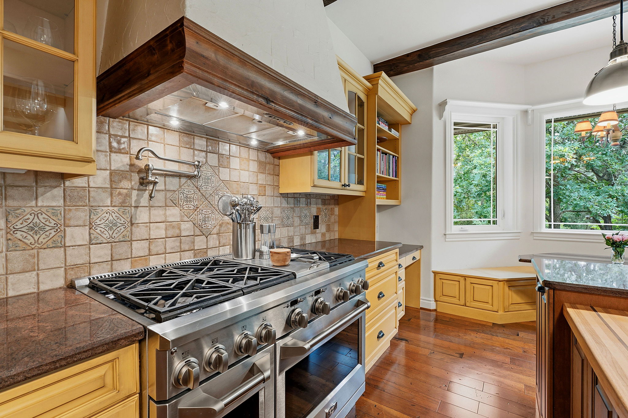 8121 Bluff Trail Austin, TX 78737 - Photo 5 of 40 Gourmet kitchen features a professional-grade range, rich wood flooring, and ample natural light from surrounding windows.