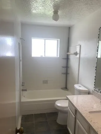 a bathroom with a granite countertop toilet a sink and bathtub
