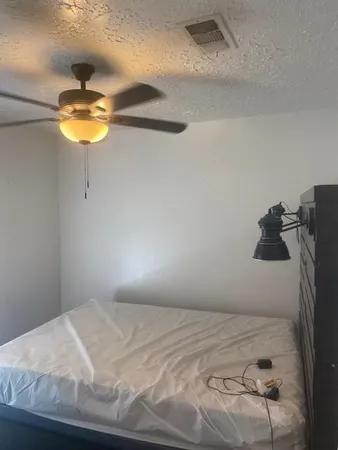a bedroom with a bed and a chandelier fan