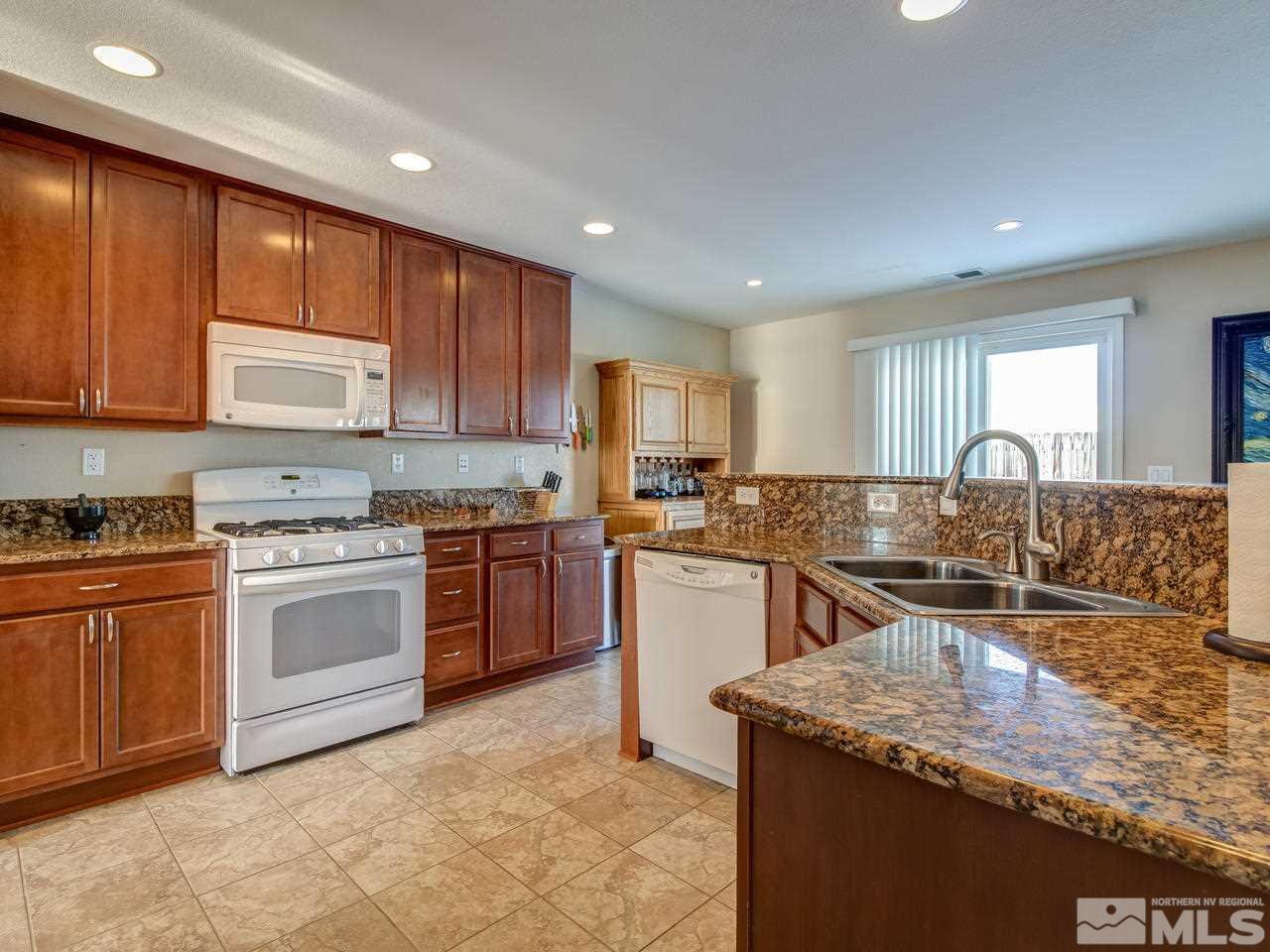 9055 Convair Way Reno, NV 89506 - Photo 2 of 24 a kitchen with stainless steel appliances granite countertop wooden cabinets a stove top oven a sink and dishwasher
