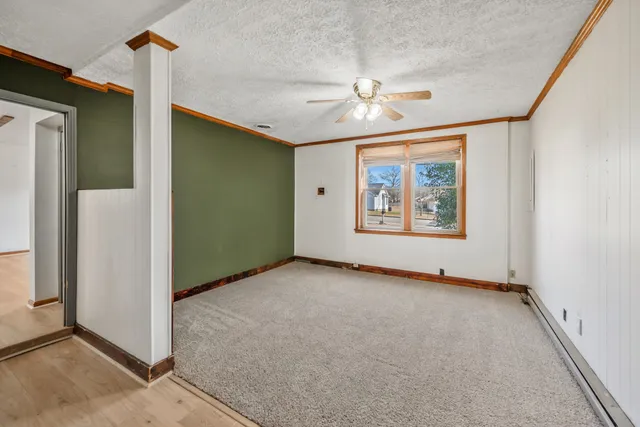 an empty room with windows and fan