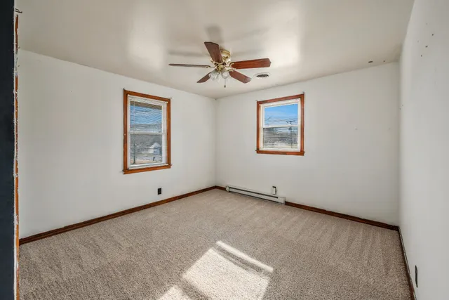 an empty room with windows and fan