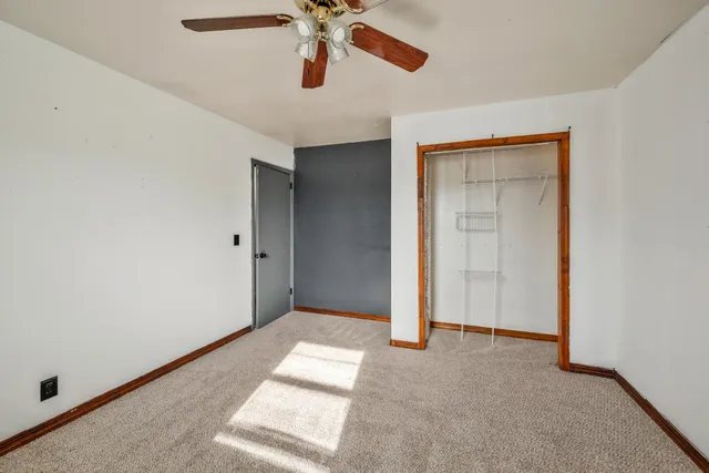 an empty room with a ceiling fan and carpet