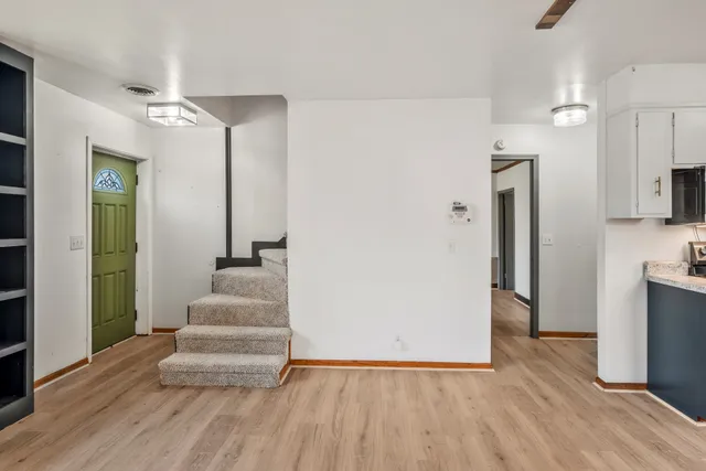 a view of an entryway with wooden floor and a kitchen view
