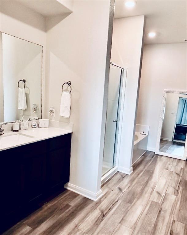 196 Cattlemans Crk Road West Newark, TX 76071 - Photo 13 of 31 Spacious bathroom featuring wood-finish flooring, a double vanity with a light-colored countertop, and a glass-enclosed shower