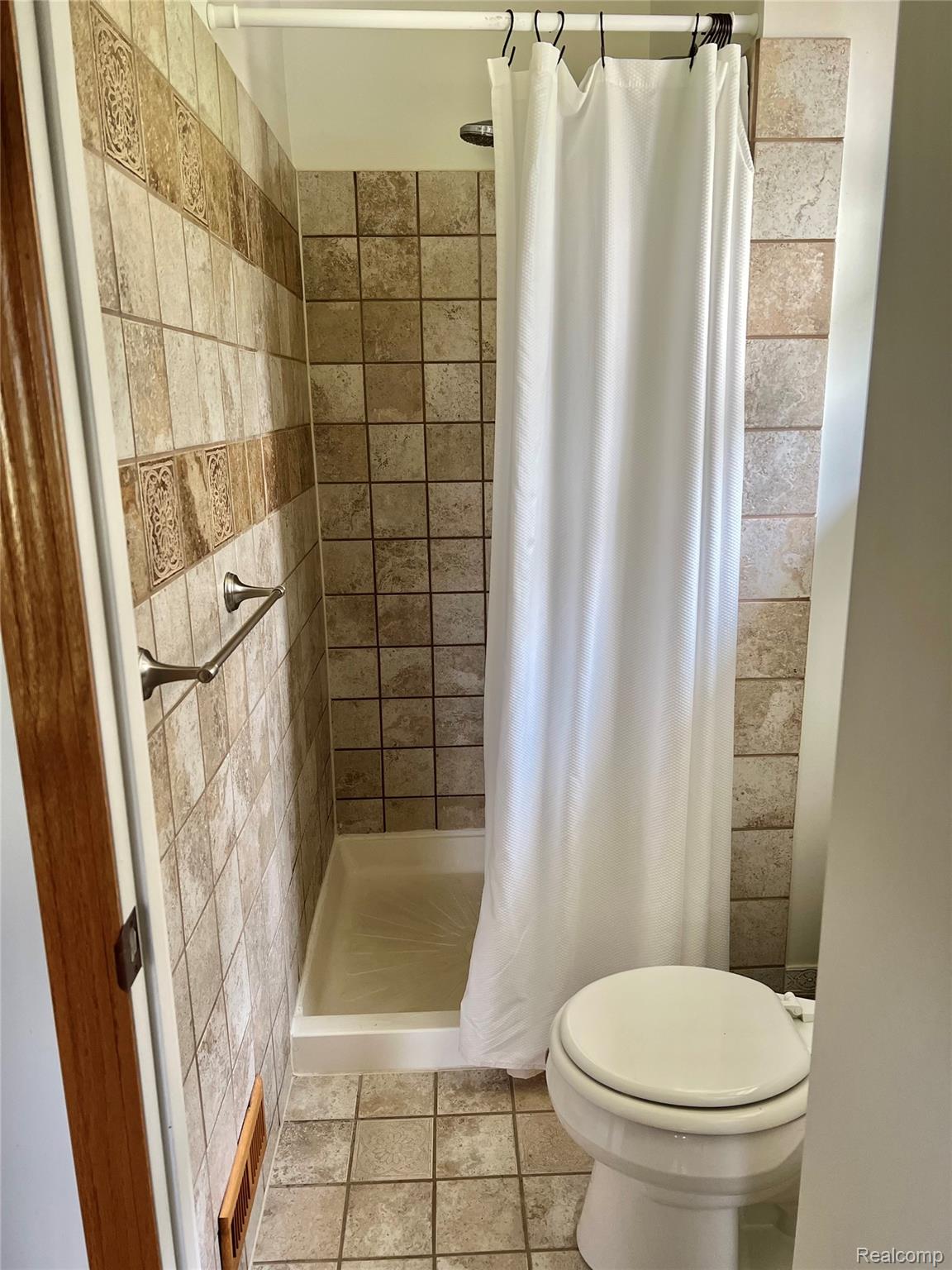 5417 North Road North Street, MI 48049 - Photo 12 of 30 Shower with beige square tile surround, decorative accent band, and an enclosed shower base