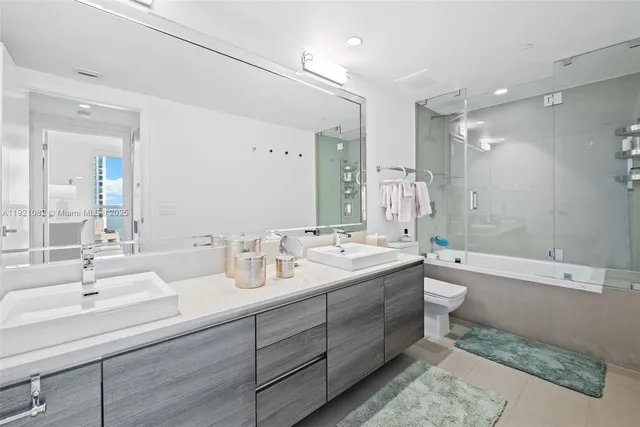a bathroom with a double vanity sink toilet mirror and bathtub