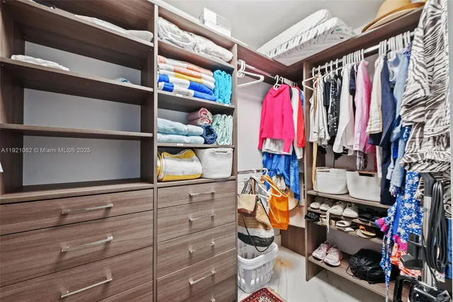 a view of walk in closet with clothes and shoes