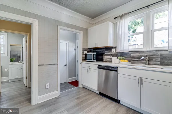 a view of a white house with a big yard plants and large trees