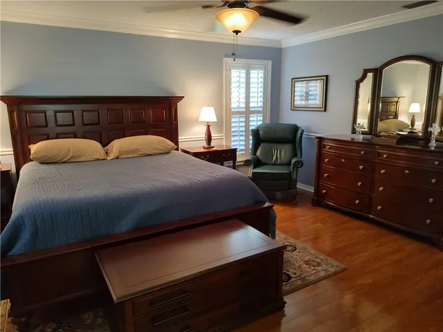a bedroom with a bed a dresser and wooden floor