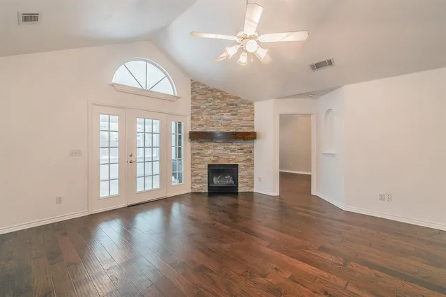 an empty room with wooden floor fireplace and windows