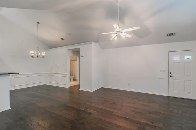 an empty room with wooden floor and ceiling fan