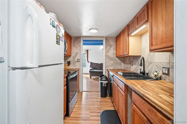 a kitchen with stainless steel appliances granite countertop a refrigerator a sink dishwasher a stove and a dining table with wooden floor