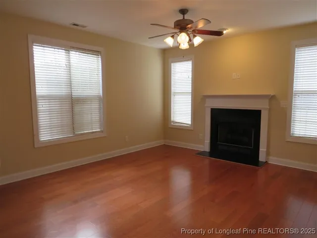 a view of an empty room with window and chandelier fan