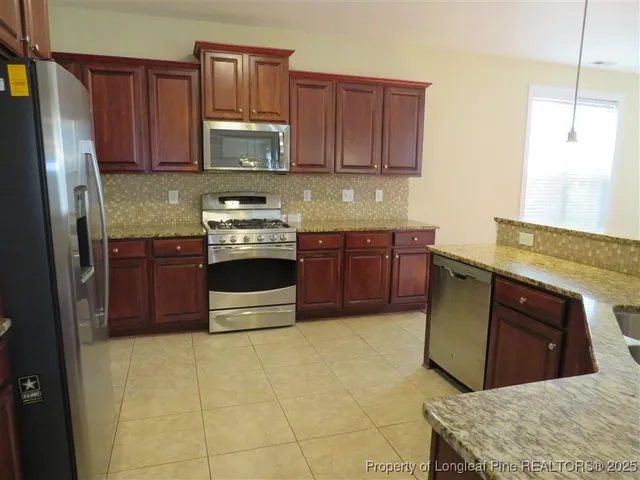 a kitchen with stainless steel appliances granite countertop a stove a refrigerator and a sink