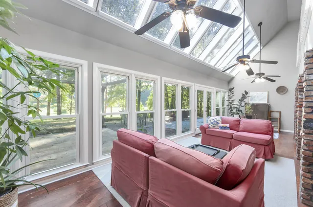 a living room with furniture a floor to ceiling windows and garden view