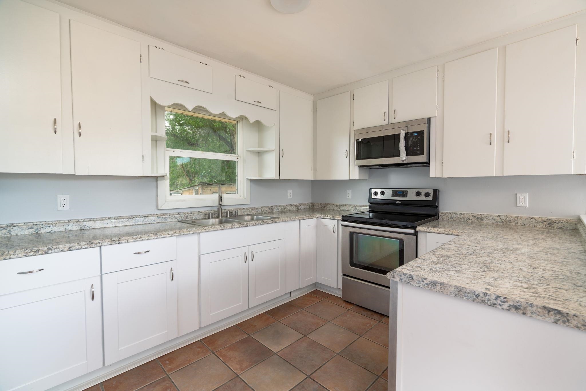 6038 Townsend Road Delta, CO 81416 - Photo 23 of 42 a kitchen with granite countertop white cabinets sink and stainless steel appliances