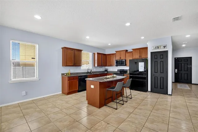 a kitchen with granite countertop a sink a stove counter space and cabinets
