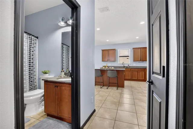a bathroom with a granite countertop sink a toilet a mirror and shower curtain