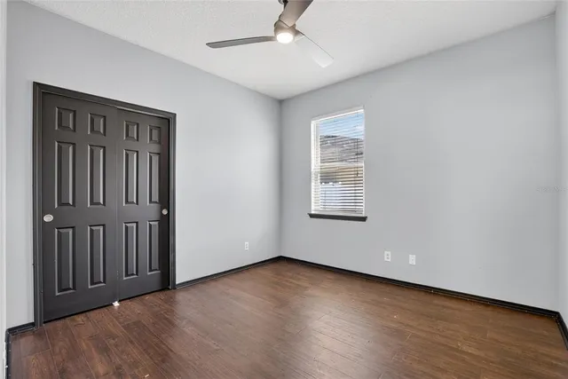 a view of an empty room with wooden floor and a bathroom