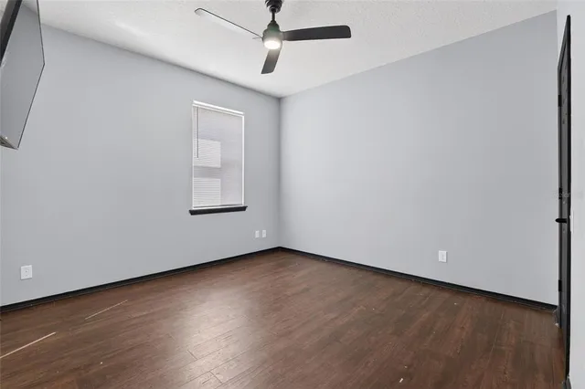 an empty room with wooden floor cabinet and windows