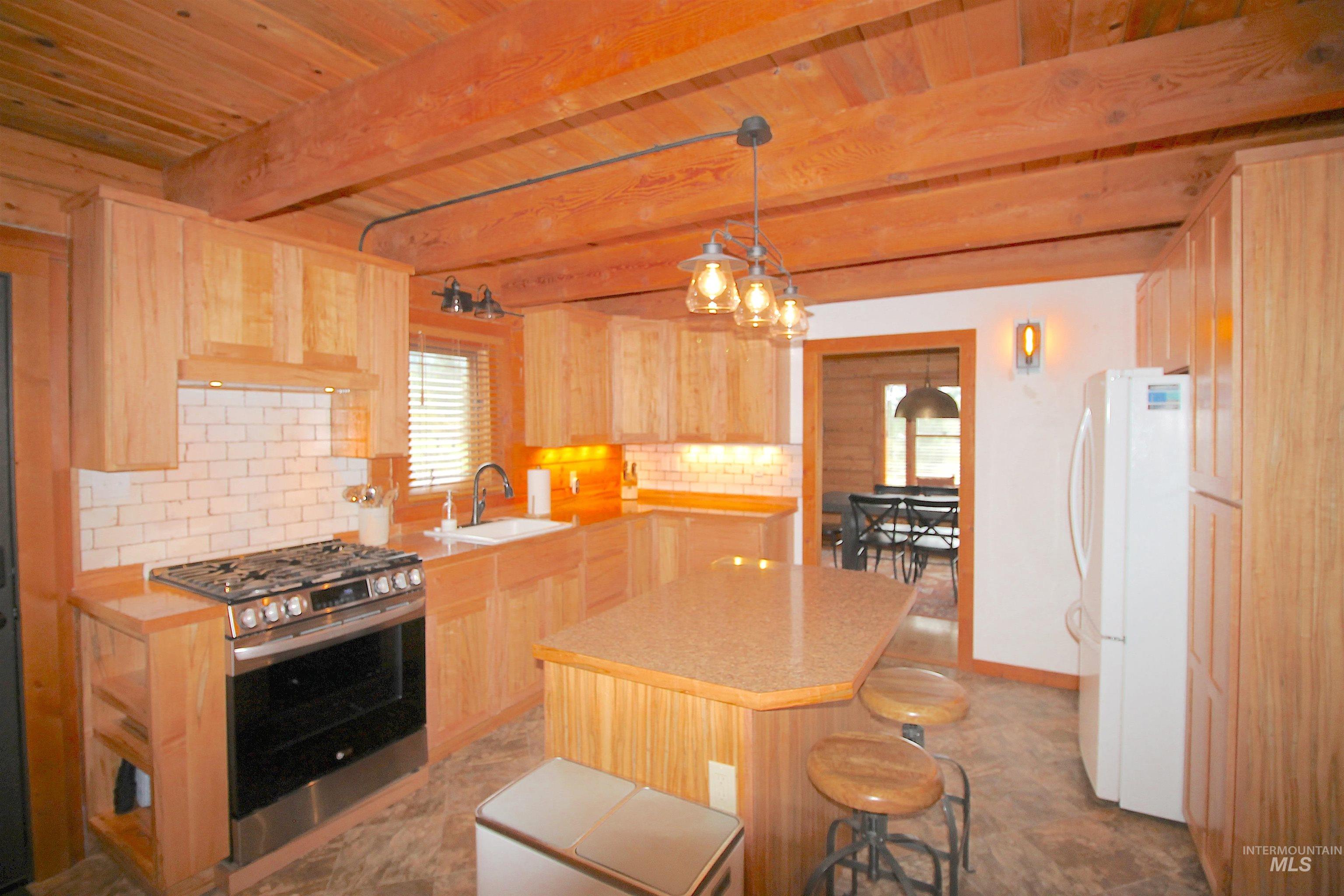 2609 Highway 95 Council, ID 83612 - Photo 23 of 49 Kitchen with light countertops, gas range, light wood finish cabinetry, decorative backsplash, and freestanding refrigerator